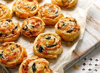 French Puff Pastry Pinwheels stuffed with salmon, cheese and spinach on on baking paper, close up view  - 402812067