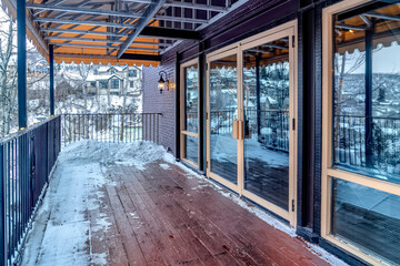 Front deck of building with double glass door and snow on the wooden floor