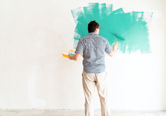 Man coloring wall green with a roller