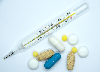 mercury thermometer with medicines on a white background