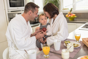 Happy family  enjoying breakfast in the kitchen with their baby