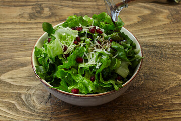 green salad, cheese and pomegranate on wooden table. healthy diet. - 402814247