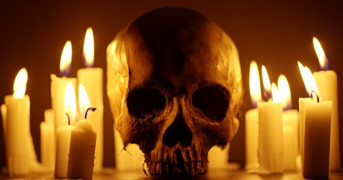 Candles and human skull in darkness closeup footage
