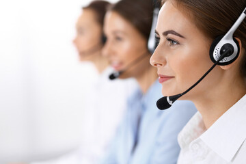 Call center. Group of operators at work. Focus on beautiful business woman in headset