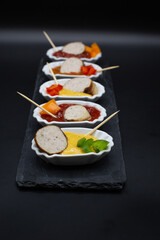 Single small plates with bratwurst and various dips in a row