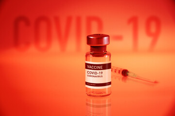 Covid-19 vaccine bottle and syringe on a red background