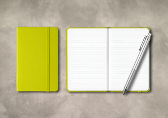 Lime green closed and open lined notebooks with a pen on concrete background