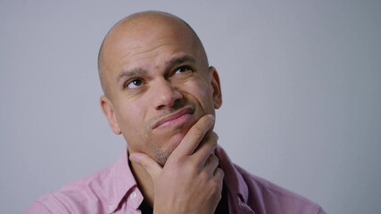 Young man looking to camera wondering about something before looking confidently to camera and smiling, in slow motion
