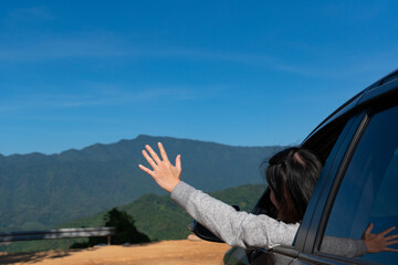 Fototapeta premium young woman heading out of car and waving hand to enjoy beautiful of mountain during vacation