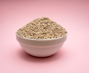 Dry oatmeal in a white bowl on a pink background. Ready to eat.