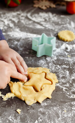 A cute 3-4 year old girl makes her own Christmas cookies. Family vacation at home during the holidays. Flour and dough. New Year's and Christmas. Child holding dough in his hands