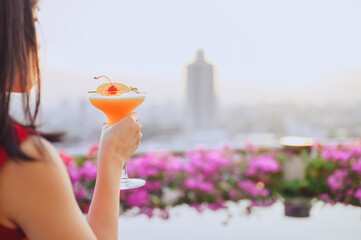 Happy asian woman while drinking cocktail at the rooftop restaurant