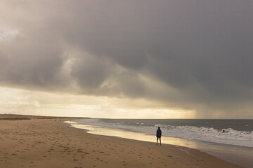 silhouette sur une plage au bord de la mer avec un ciel tourmenté