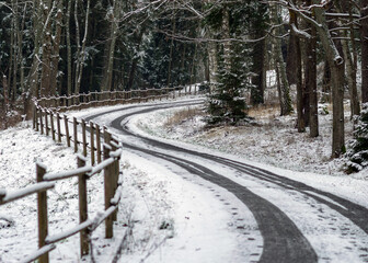 winter landscape with snowy road, snow-covered wooden fence, trees and shrubs by the road, winter