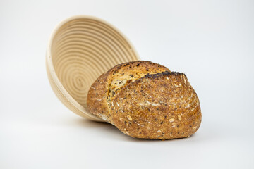 A bread with seeds on a white background  and near it a wooden rounded vessel