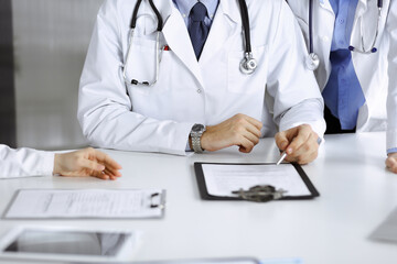Group of unknown doctors are sitting at the desk and discussing problems or disease treatment in modern hospital office. Coronavirus countering, patient help in medicine concept