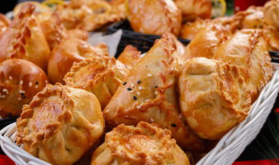 different types of small pies in a basket on a dark background. Bakery products. Catering. Delivery