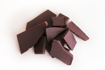 Heap of broken dark chocolate. White background.