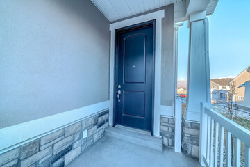 Hinged front door of house with porch that looks out to the snowy neighborhood