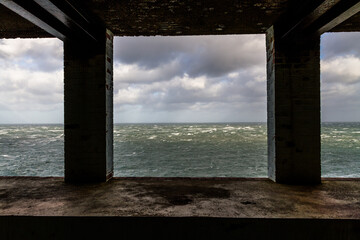 Lookout in derelict building looking out to stormy sea with two pillars.