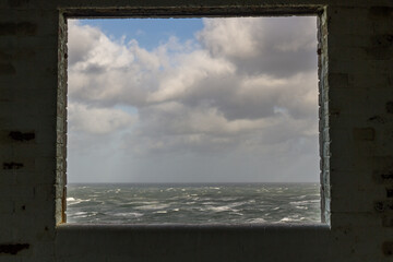 Window frame in derelict building looking out to stormy sea.