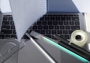 
Checked notebook on the laptop screen. The sheets are turned over. Pencils ballpoint pens...