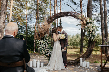 Man taking a picture of kissing bride and groom at the wedding ceremony. Happy newlyweds at the...