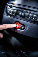 Fototapeta premium Pressing a hazard warning lights button on a car dashboard.