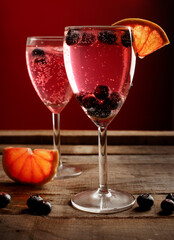 two glasses with red cocktail on a rustic wooden table