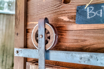 Close up of the wooden wheel and metal track of a rustic bathroom sliding door