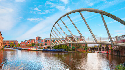 Waterway canal area with a narrowboat on the foreground modern bridge, Castlefield district -...