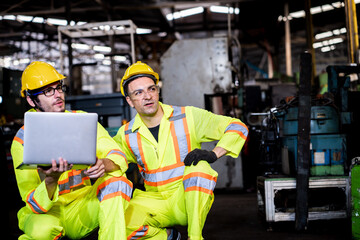 Worker two man caucasian talking and use laptop computer at factory in protective safety jumpsuit uniform with yellow hardhat.Metal working industry concept professional engineer manufacturing machine