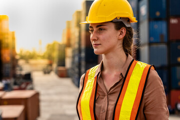 Caucasian women head of container yard control wearing yellow safety helmets with containers in background