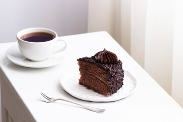 Chocolate cake and coffee, still life in a light interior.