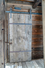 Locked sliding wooden door of an old outdoor bathroom with chain and padlock
