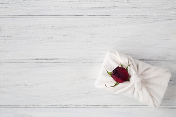 Valentines zero waste concept. Eco friendly gift with dried rose on the white wooden background with copy space