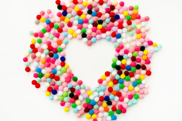 Colored pompoms in the form of heart on white background.Handmade love decoration.