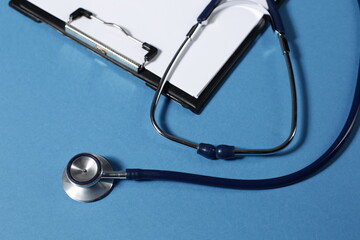 Stethoscope and tablet for recording patients on blue background