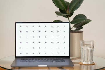 Laptop's front view mock-up with coffee and flower home decor in vase on glass table, with plant in background, blank screen for your design, with free space for your text about business