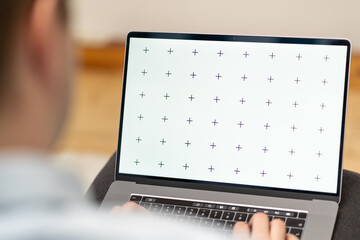 Man with glasses holds laptop in lap, browsing internet or application with blank screen mock-up...