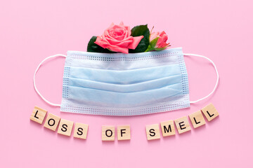 Loss of smell, anosmia. COVID19 symptom. Medical mask and roses on a pink background, concept.