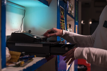 Un camarero abriendo una caja registradora en un bar de noche