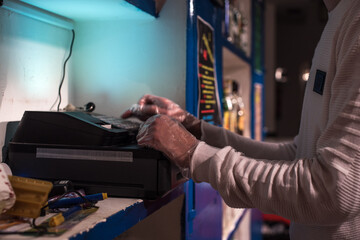 Las manos de un camarero sacando dinero de la caja registradora abierta de un bar de noche usando guantes como prevención
