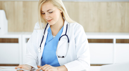 Woman-doctor standing in hospital or clinic and using tablet pc. Data and best service in medicine and healthcare