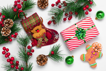 White Christmas card with gingerbread man and stocking decorated with felt reindeer. Festive New Year background. Cookies and decorations made from green spruce tree branches and red holly berries.