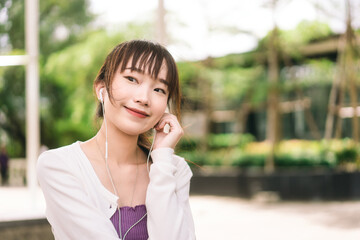 Happy young adult asian woman listening streaming music at outdoor on day.