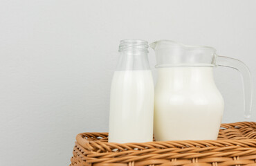 A jug and bottle of fresh milk glass on wooden basket background.Raw milk is high in calcium and protein to drink for all ages..Milk consumption nutritious and healthy dairy products concept.
