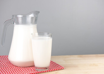 A jug and bottle of milk glass on a wooden table on background..Raw milk is high in calcium and protein to drink for all ages..Milk consumption nutritious and healthy dairy products concept..