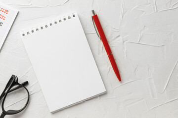 Blank notepad, pen, eyeglasses and calendar on white putty texture background. Notebook for notes...