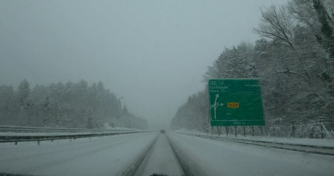 Dashcam dash camera POV slow driving on snowy highway road in Slovenia. Snowstorm in winter season. Snow covering motorway in blizzard. Forward dolly moving, wide angle, real time
